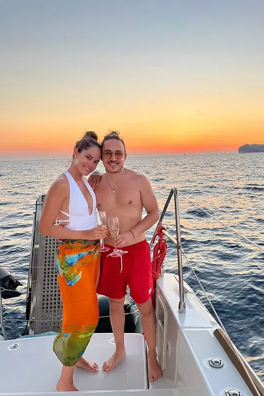 Couple toasting champagne at sunset on Santorini catamaran