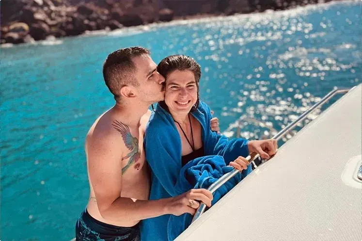 Smiling romantic couple kissing on boat at Red Beach Santorini
