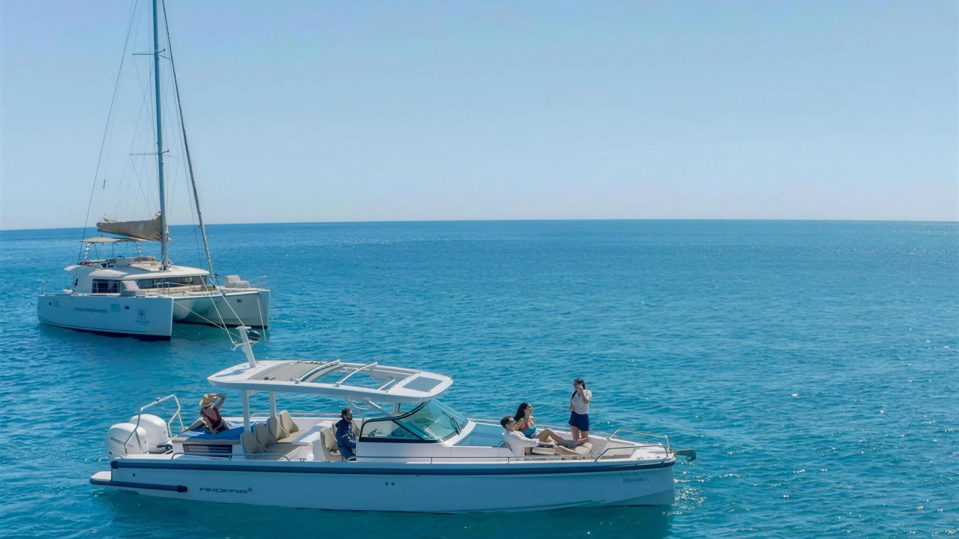 Vista Yachting's private motor yacht, an Axopar 37 Sun Top, in front of a private Lagoon catamaran off Santorini