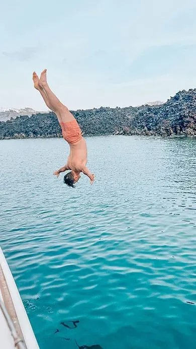 guest diving from motor yacht into turquoise Aegean Sea