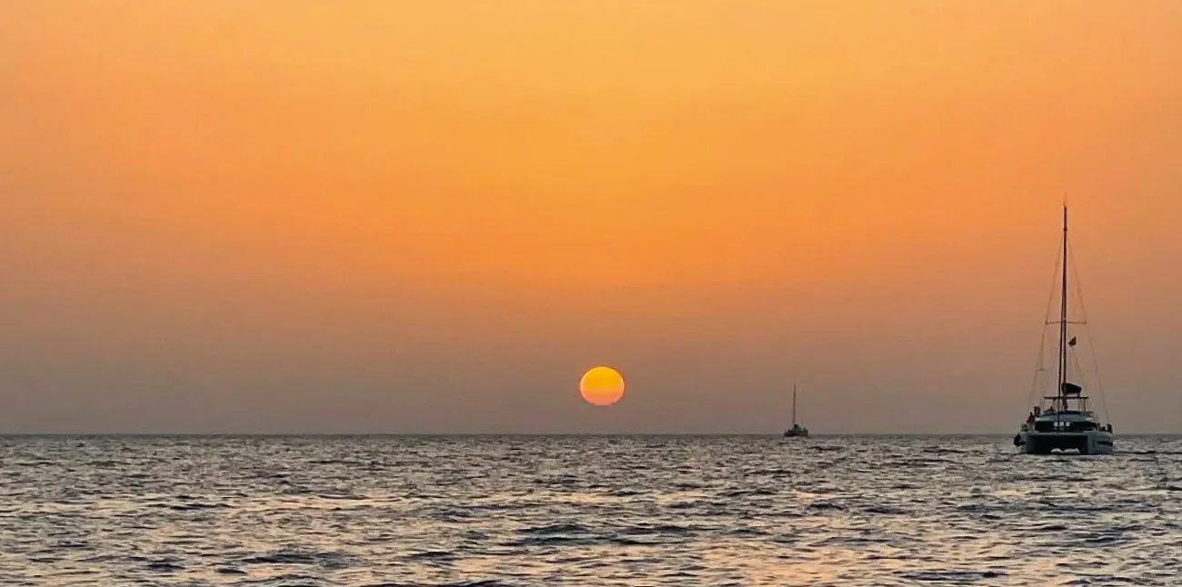 A catamaran on the sea off Santorini at sunset