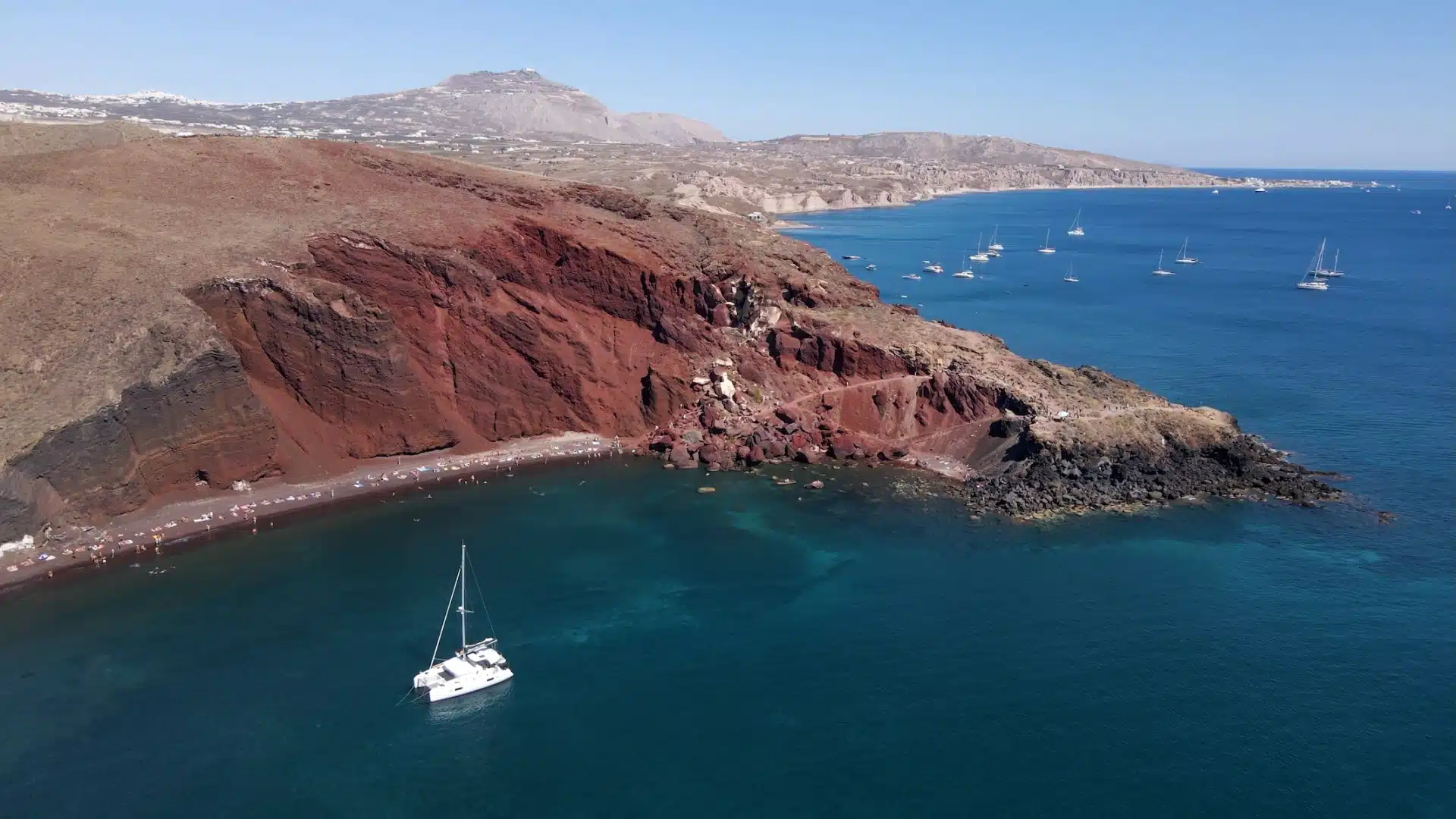 Red Beach in Santorini with its red cliffs and boats anchored in the bay