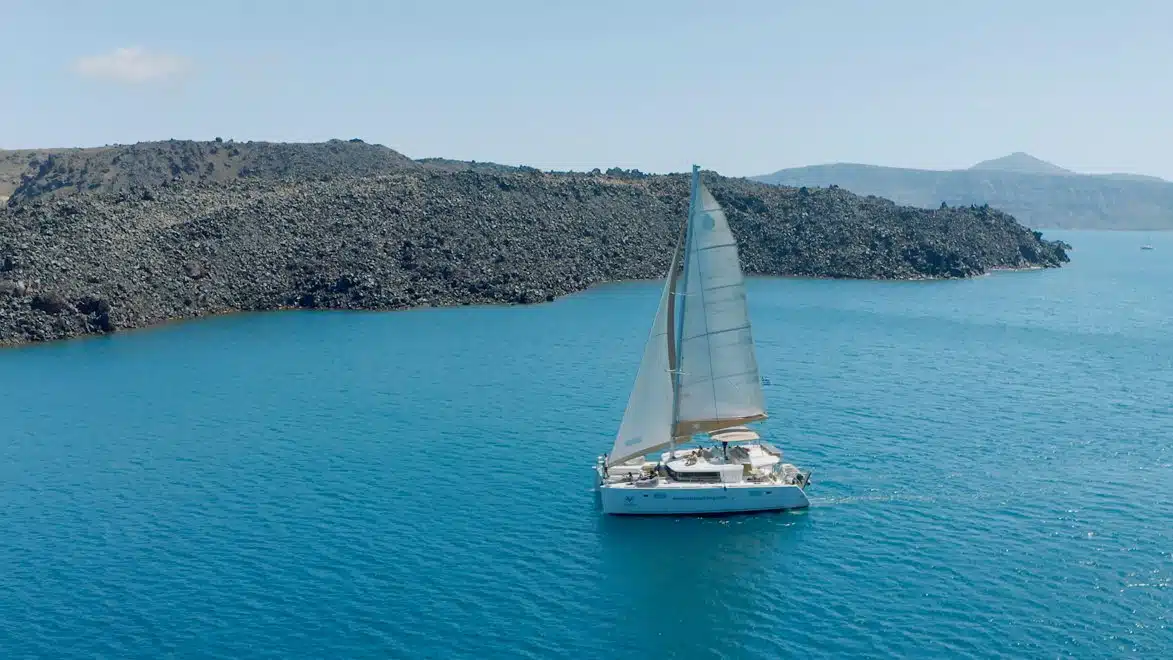 Catamaran under sail off the volcanic islands in the Santorini caldera